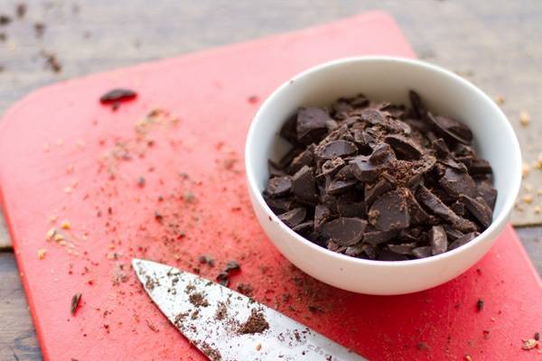 Chopped chocolate on a red cutting board.